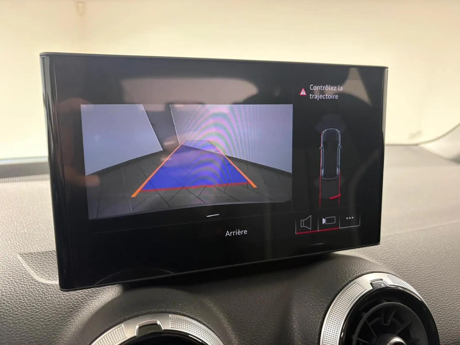 Écran intérieur montrant la caméra de recul avec guidage de trajectoire d’un Audi Q2 Noir Mythic, vue de face.