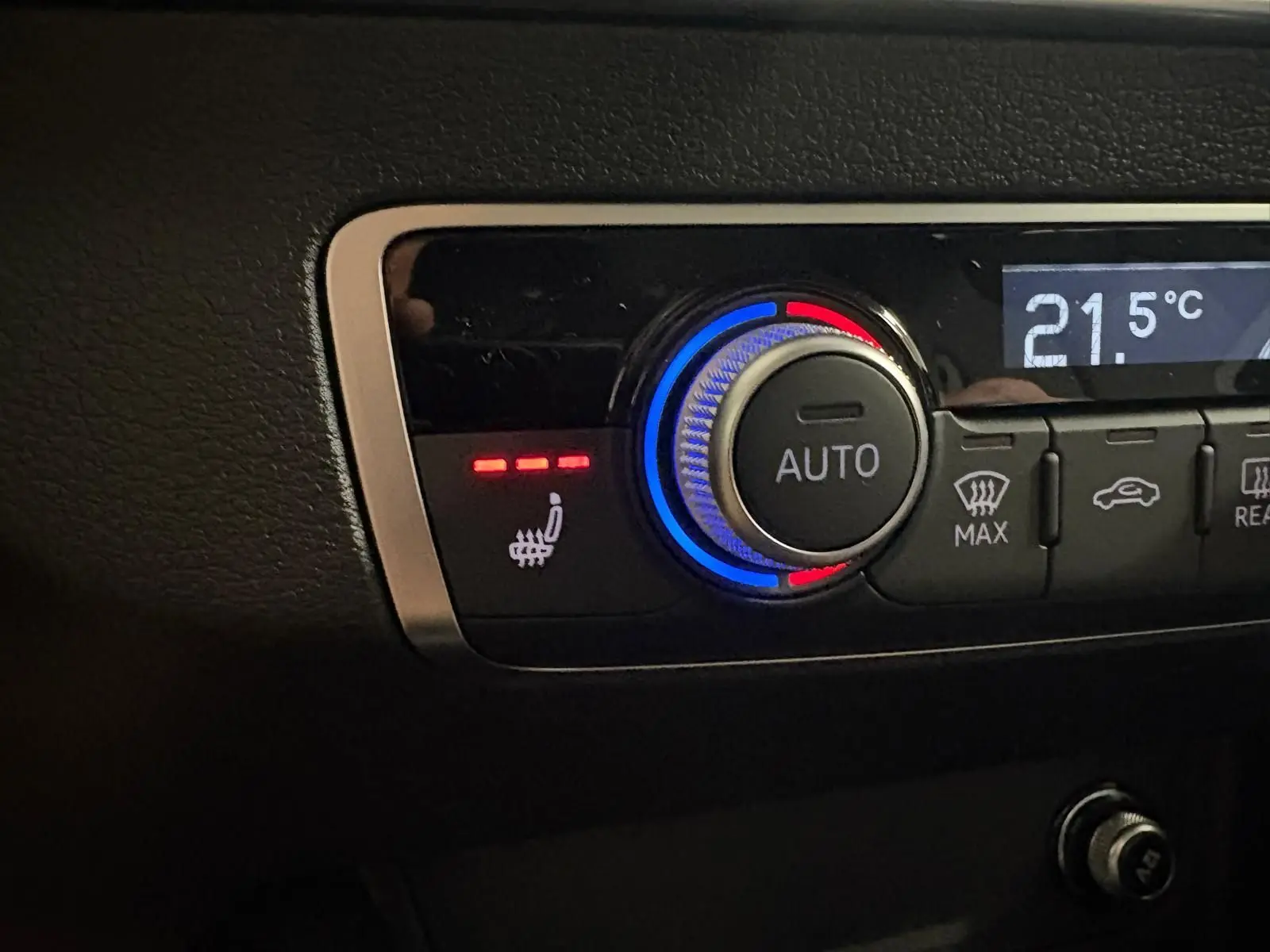 Détail du bouton de réglage de la climatisation avec fonction siège chauffant activée sur Audi Q2 Noir Mythic.