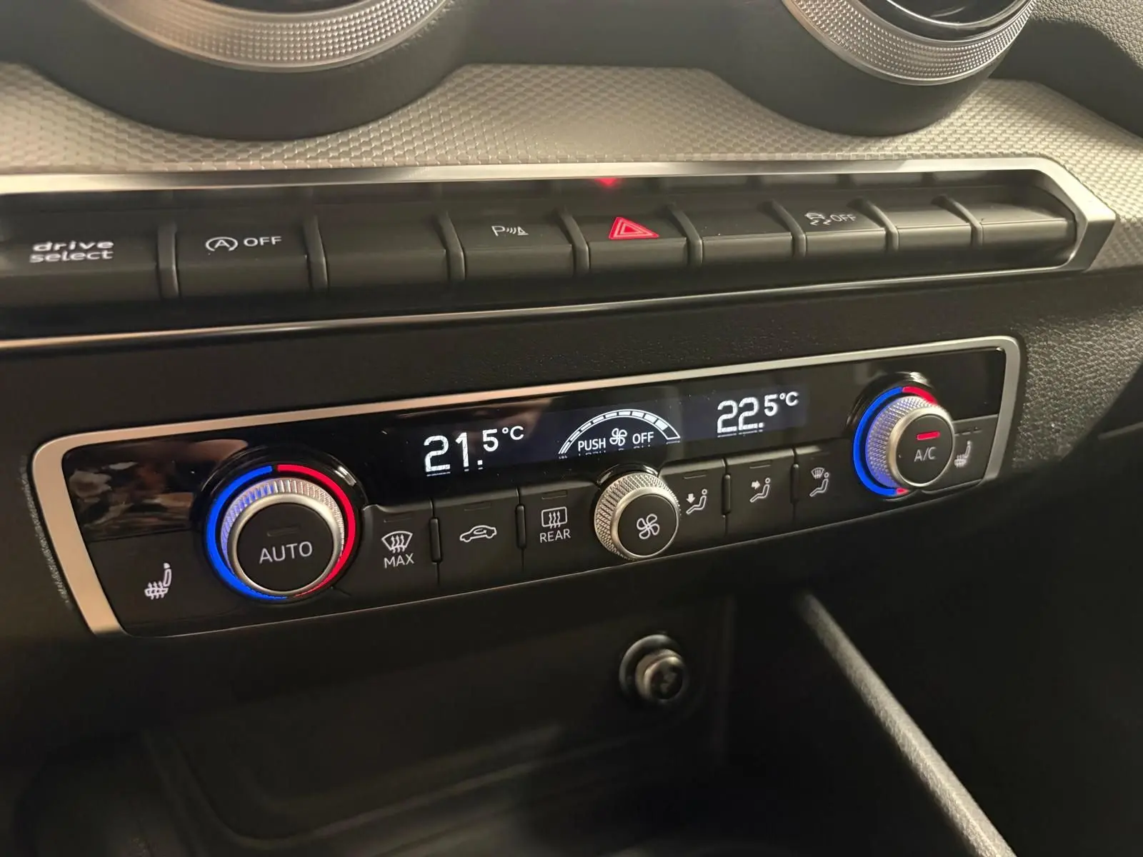 Gros plan sur la console de climatisation automatique de l'Audi Q2 35 TFSI S Line avec réglages digitaux et boutons rétroéclairés.