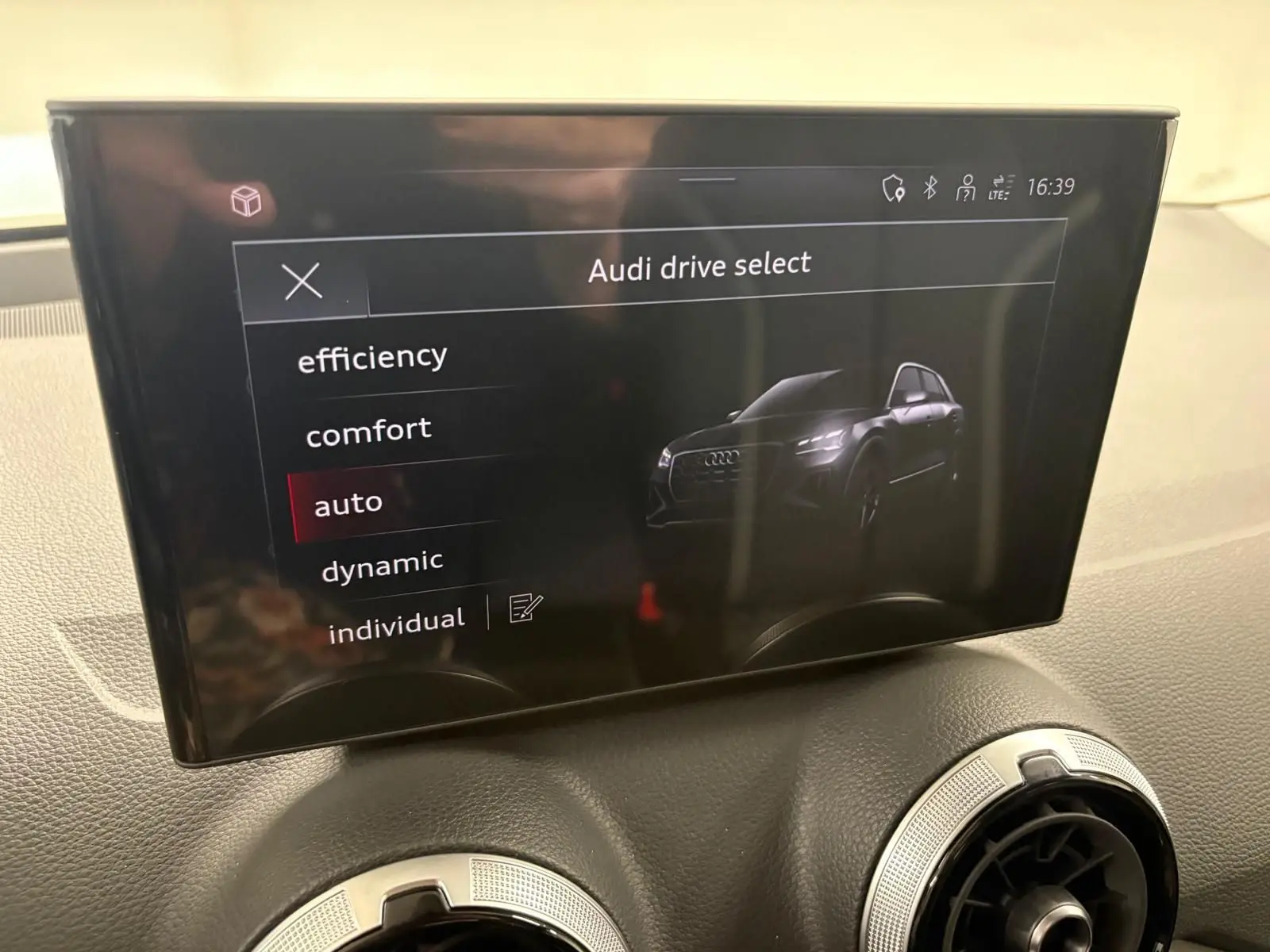 Écran central de l'Audi Q2 35 TFSI S Line 2026 affichant les modes de conduite avec une vue stylisée du SUV noir Mythic.