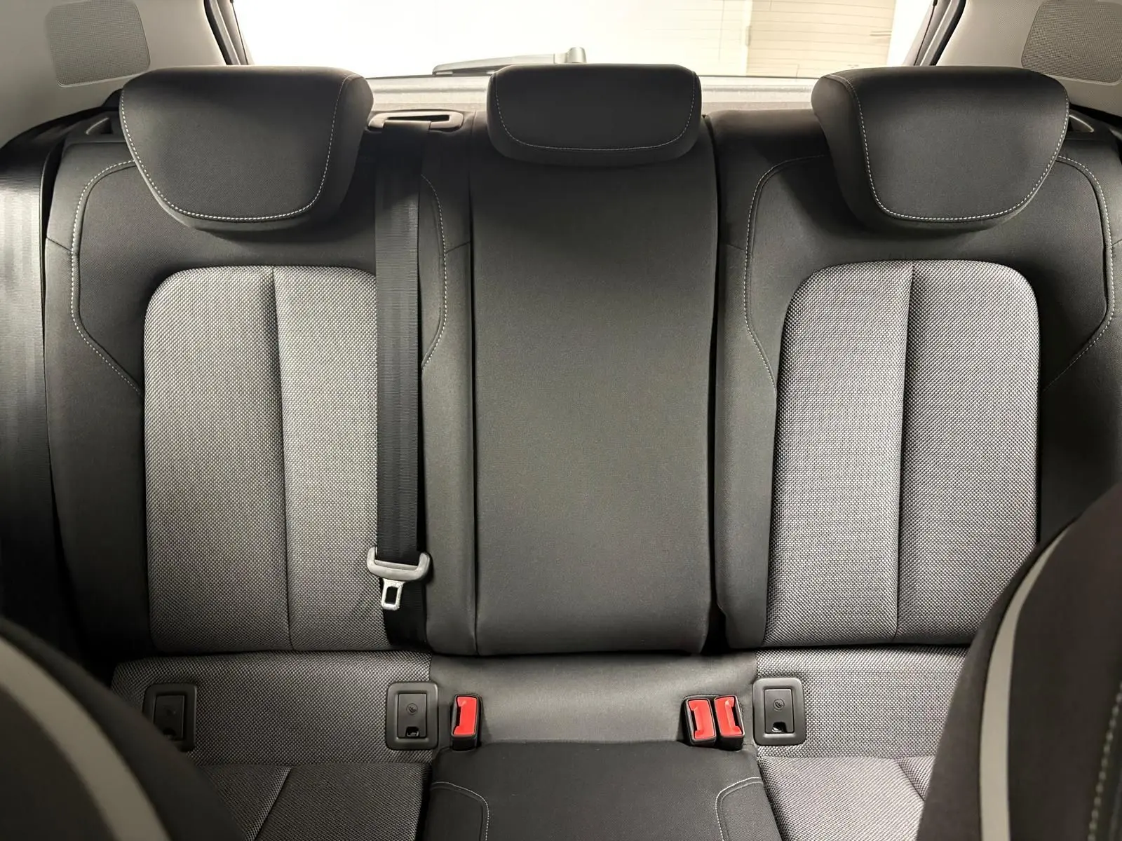 Vue arrière des sièges arrière en tissu gris et noir de l'Audi Q2 35 TFSI S Line 2026, avec ceinture et appuie-têtes.