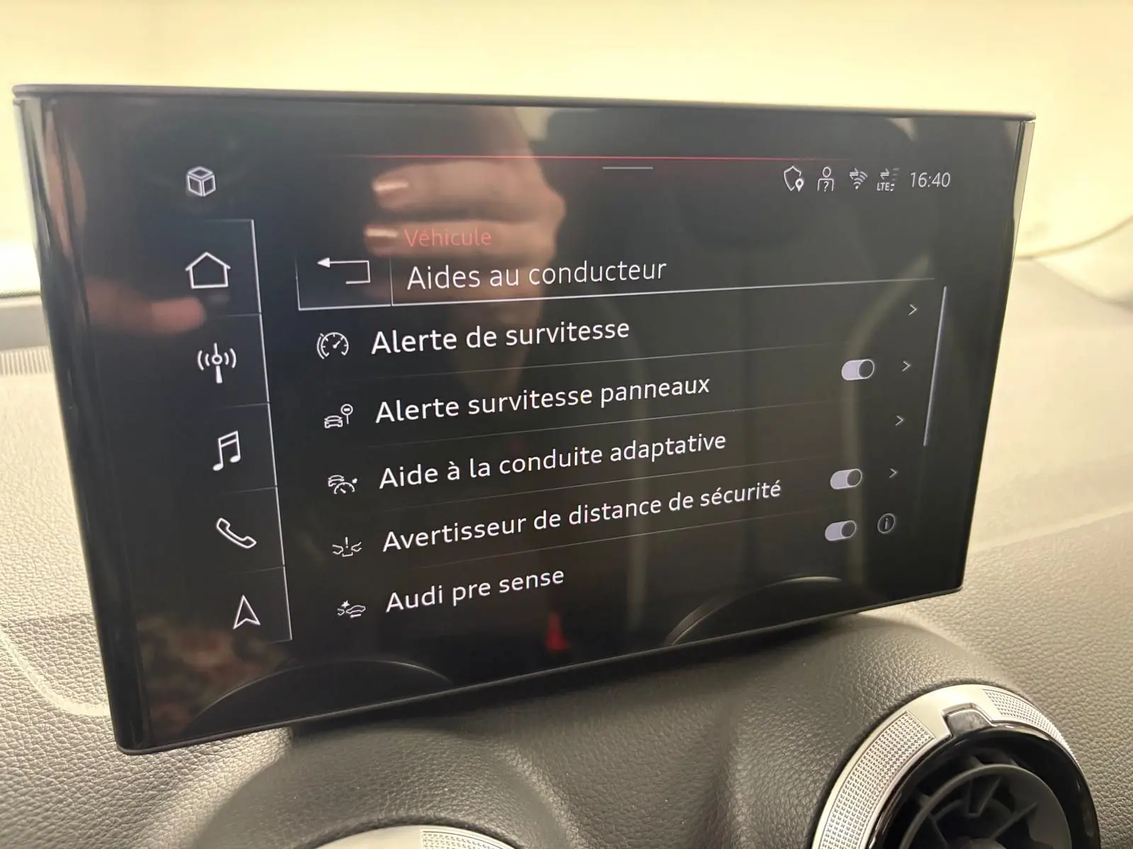 Écran central tactile de l'Audi Q2 35 TFSI S Line 2026 affichant les aides à la conduite, intérieur noir.