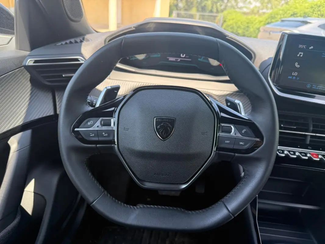 Vue intérieure centrée sur le volant noir du Peugeot 2008 Hybrid 136 e-DCS6 Style avec tableau de bord et écran tactile visibles.