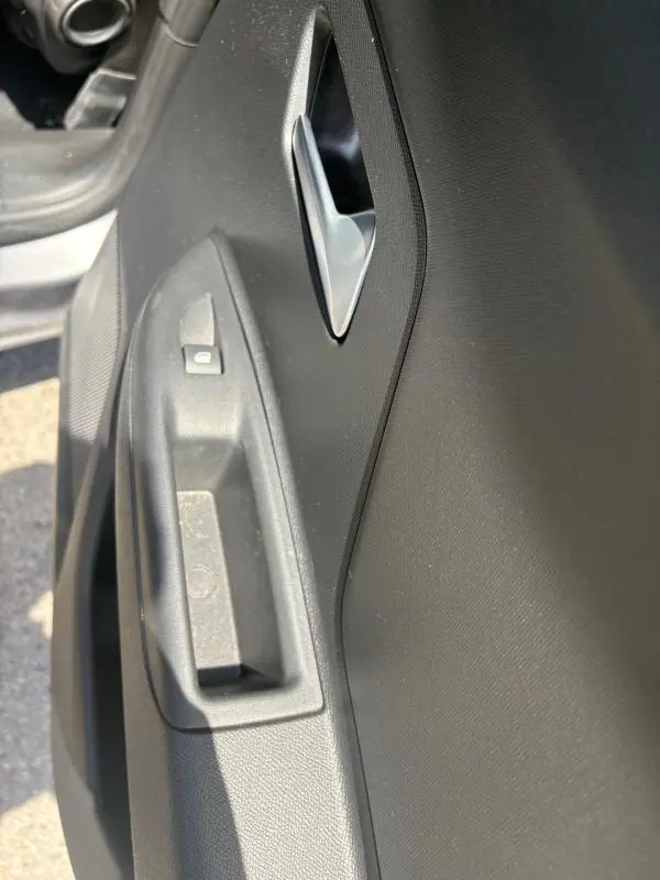 Gros plan sur la poignée intérieure et le bouton de verrouillage de la porte côté conducteur d'une Opel Mokka électrique gris 2025.