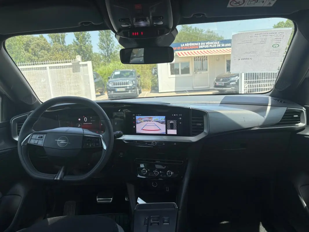 Vue intérieure avant de l'Opel Mokka électrique 2025, tableau de bord avec écran tactile et volant multifonction noir.