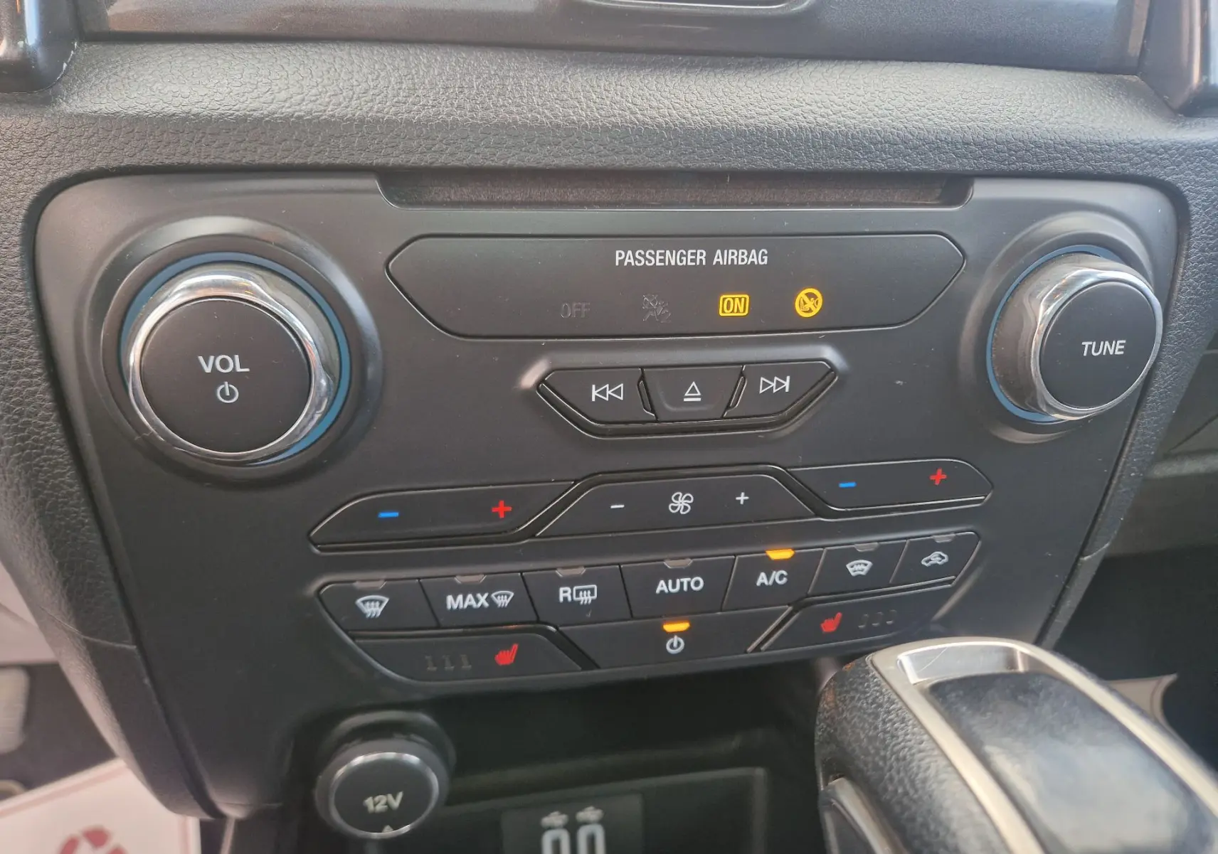 Vue rapprochée de la console centrale noire du Ford Ranger Wildtrak 2020, avec commandes climatisation et volume.