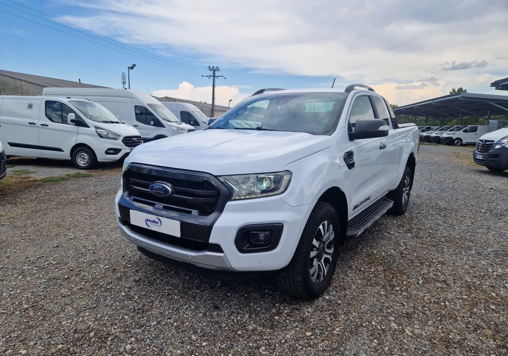 Ford Ranger Super Cabine blanc vu en 3/4 avant droit, avec marchepied et jantes alliage distinctives.