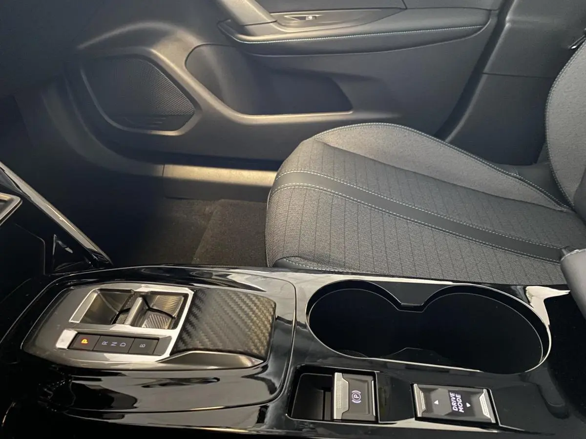 Vue rapprochée de la console centrale noire brillante et siège tissu gris du Peugeot 2008 e-136 Allure Pack 2022.