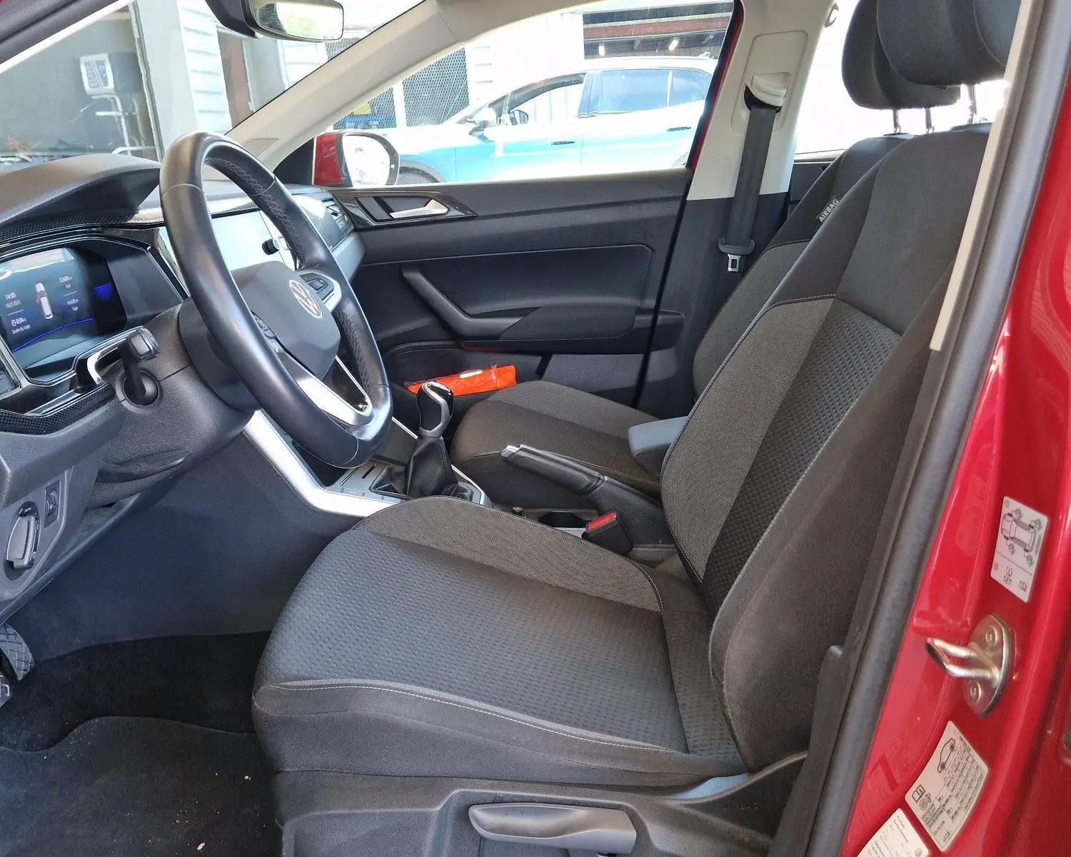 Vue intérieure côté conducteur du Volkswagen Taigo rouge roi 2023, montrant les sièges et le tableau de bord moderne.