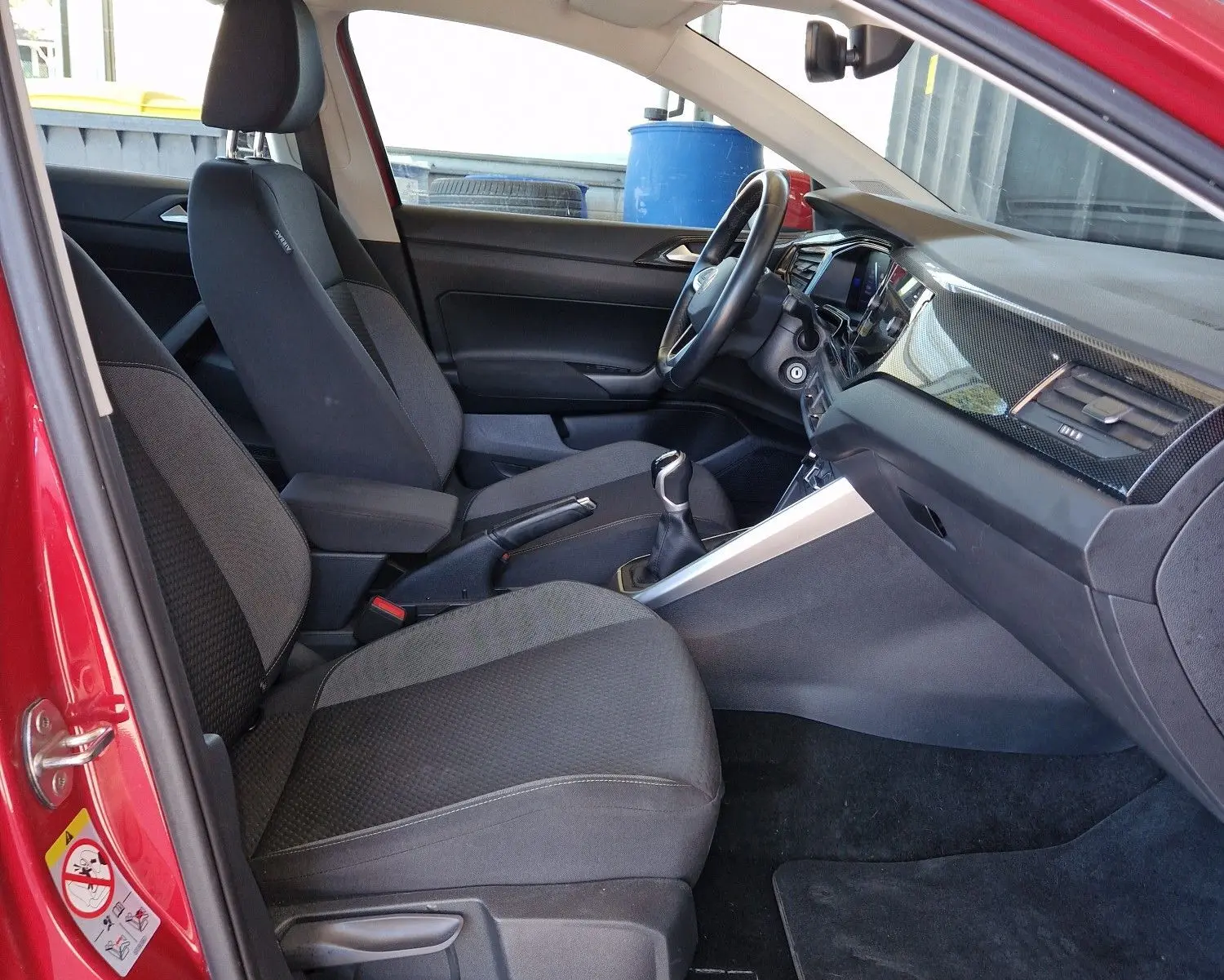 Intérieur côté conducteur du Volkswagen Taigo rouge roi 2023, avec sièges noirs et tableau de bord moderne.