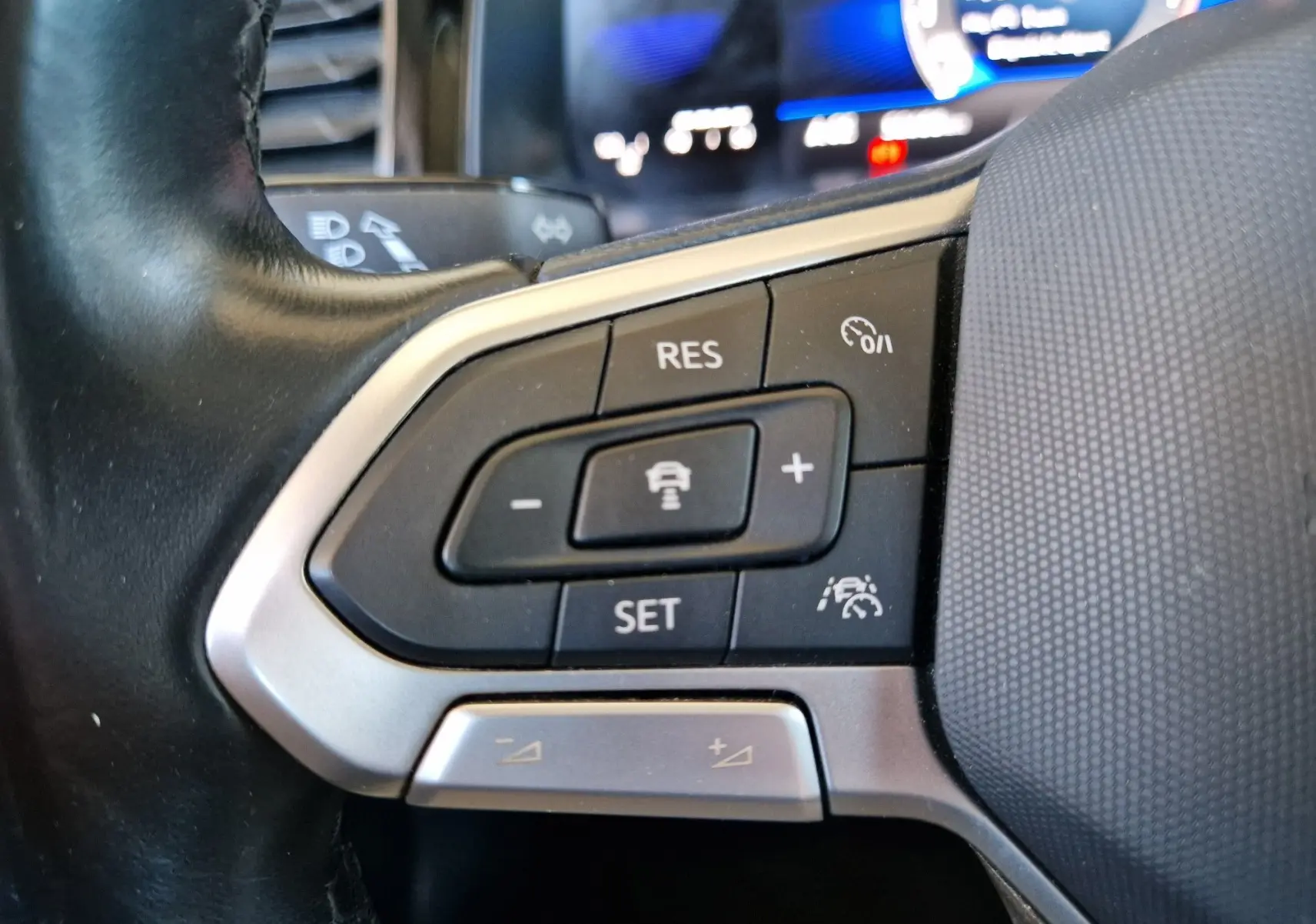 Gros plan sur les commandes de régulateur de vitesse au volant d'un Volkswagen Taigo rouge roi 2023.