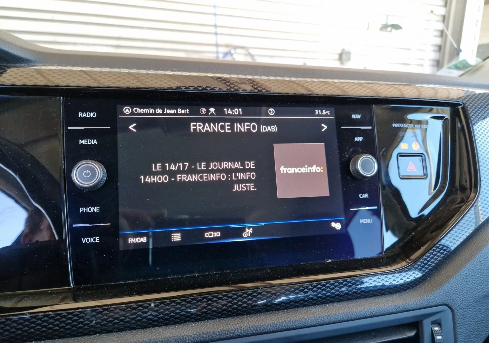 Écran tactile central du Volkswagen Taigo 2023 affichant la radio France Info avec commandes autour et finition noire brillante.