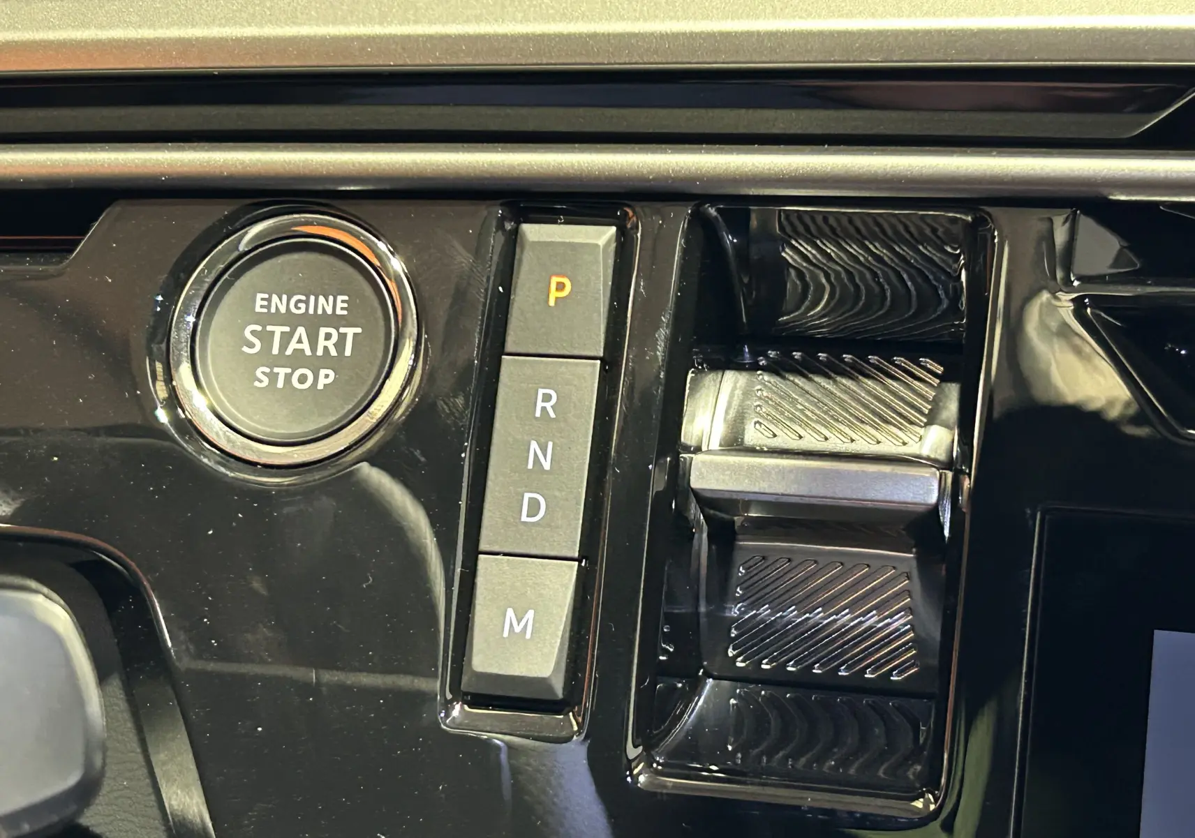 Gros plan sur la console centrale noire brillante avec bouton start/stop et commandes de boîte automatique du Peugeot 5008 bleu Ingaro.