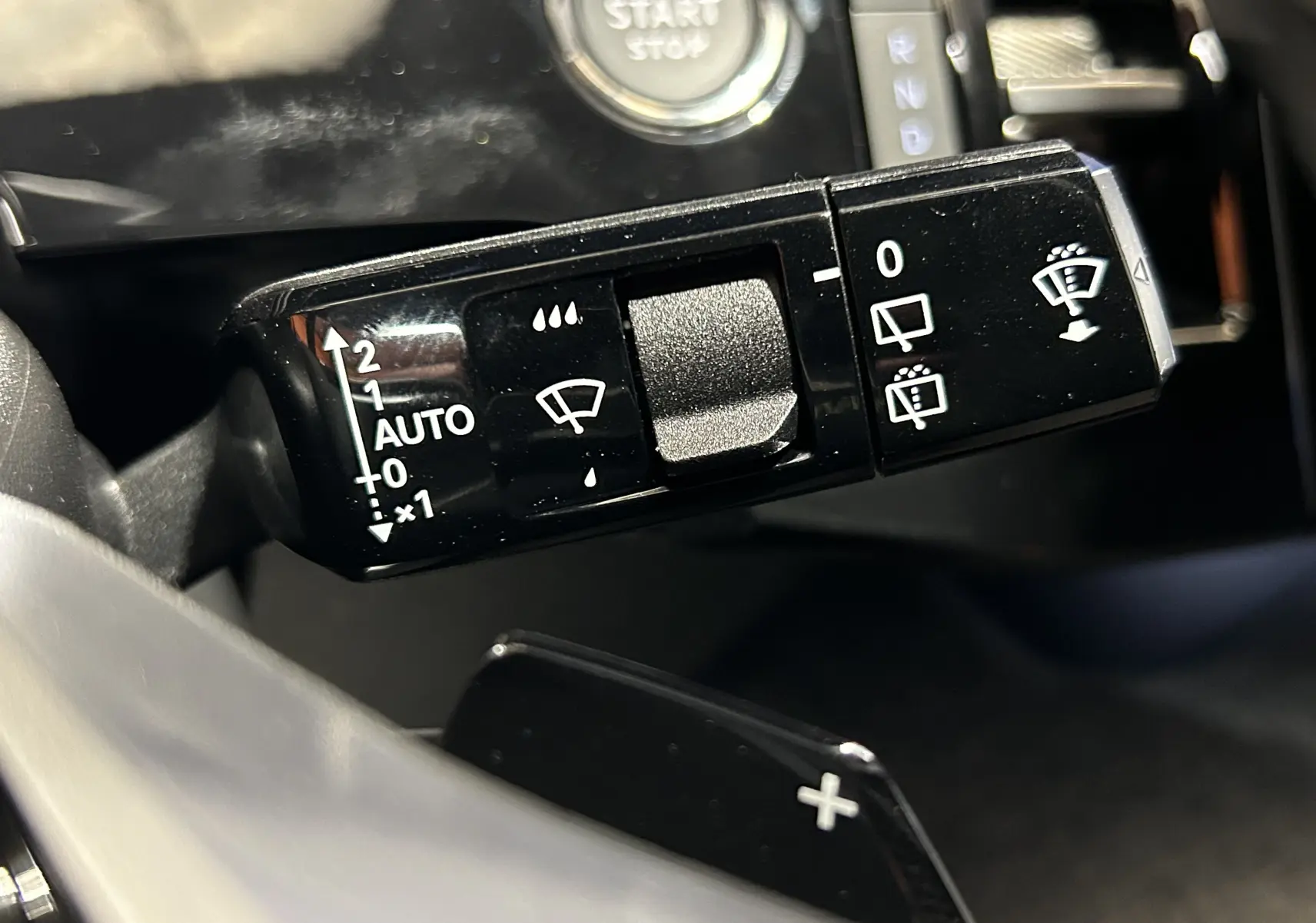 Gros plan sur la commande de l’essuie-glace côté droit du Peugeot 5008 III Hybrid 145 GT, intérieur noir brillant.