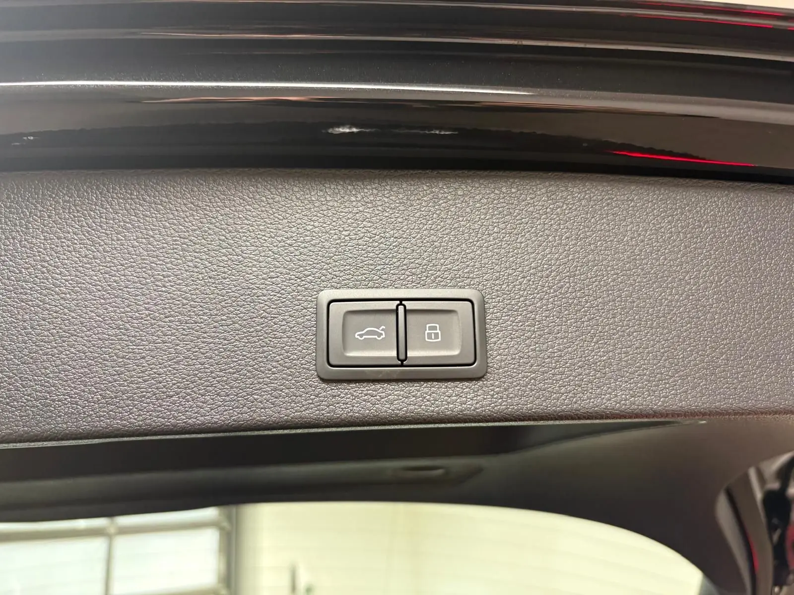 Boutons de commande du hayon électrique sur la partie intérieure du coffre d’un Audi Q2 Noir Mythic, vue rapprochée.