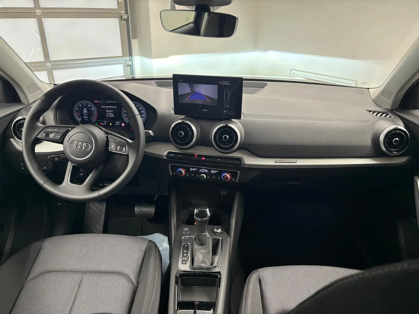 Vue intérieure de l'Audi Q2 35 TFSI S Line 2026, tableau de bord et console centrale avec écran et volant multifonction.