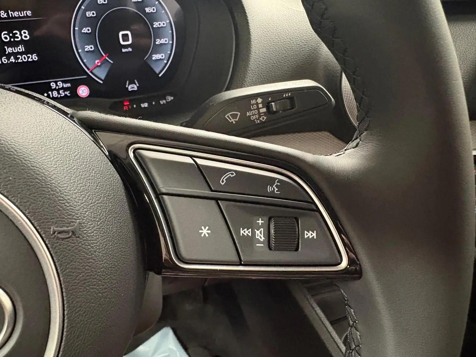 Gros plan sur les commandes du volant d’un Audi Q2 35 TFSI 150 S tronic 7 S line 2026, intérieur noir.