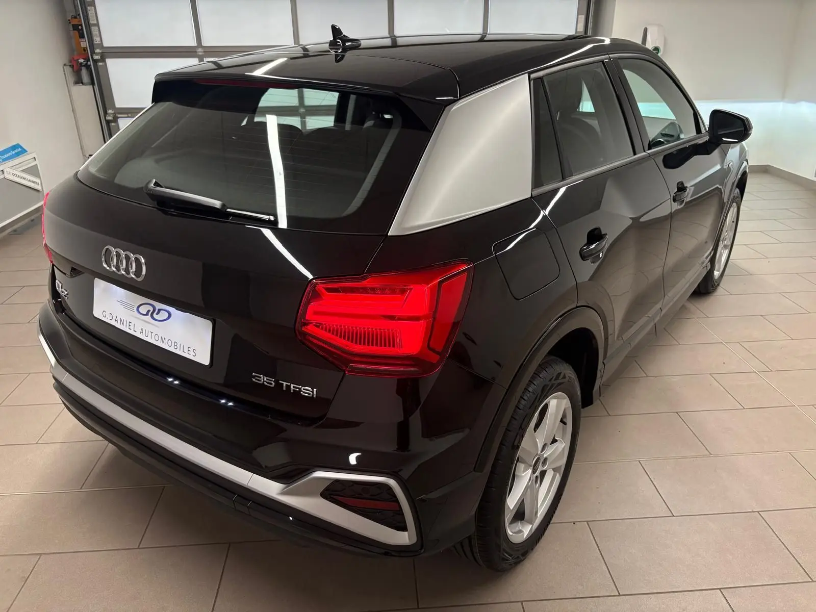 Audi Q2 35 TFSI S line noir mythic vu en 3/4 arrière droit, avec toit noir et montant arrière argenté contrastant.