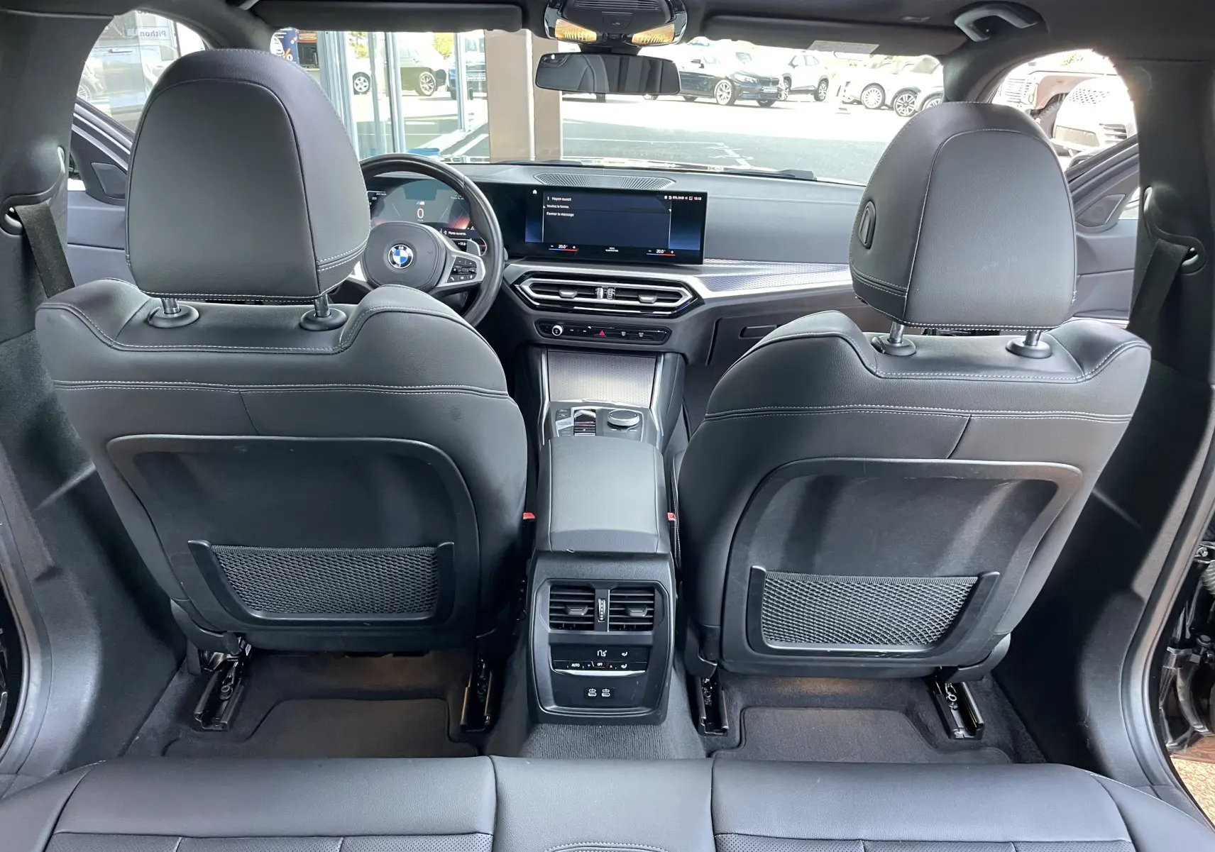 Vue arrière de l'intérieur d'une BMW Série 3 Touring G21 noir métal, avec sièges cuir noir et tableau de bord moderne.