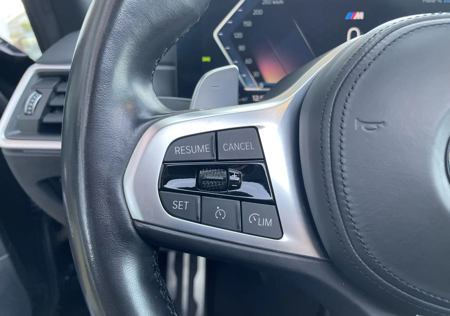 Gros plan sur les commandes de régulateur de vitesse au volant cuir noir d'une BMW Série 3 Touring G21 2022.