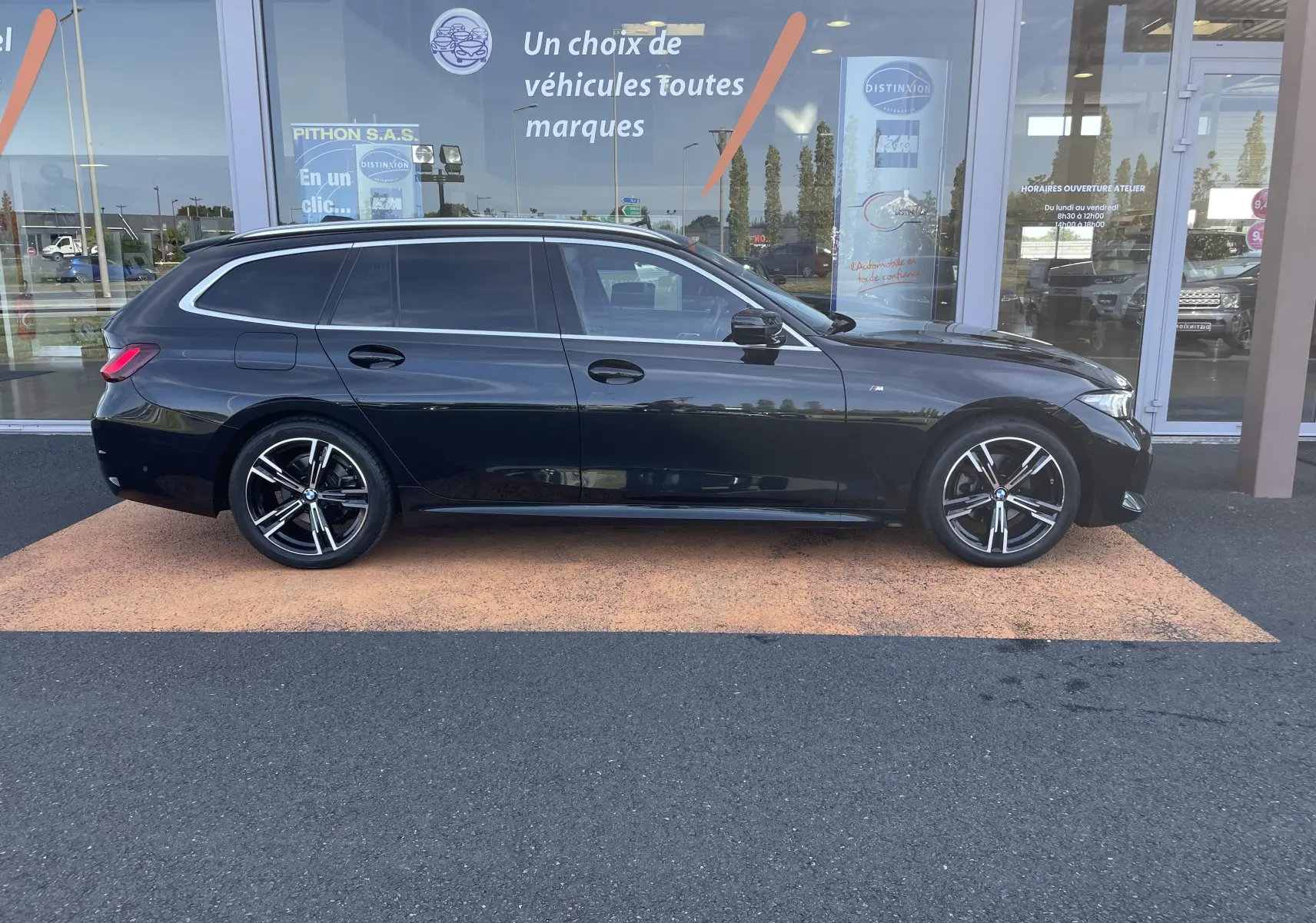 Profil latéral droit d'une BMW Série 3 Touring G21 noire métal, finition M Sport avec jantes alliage distinctives.