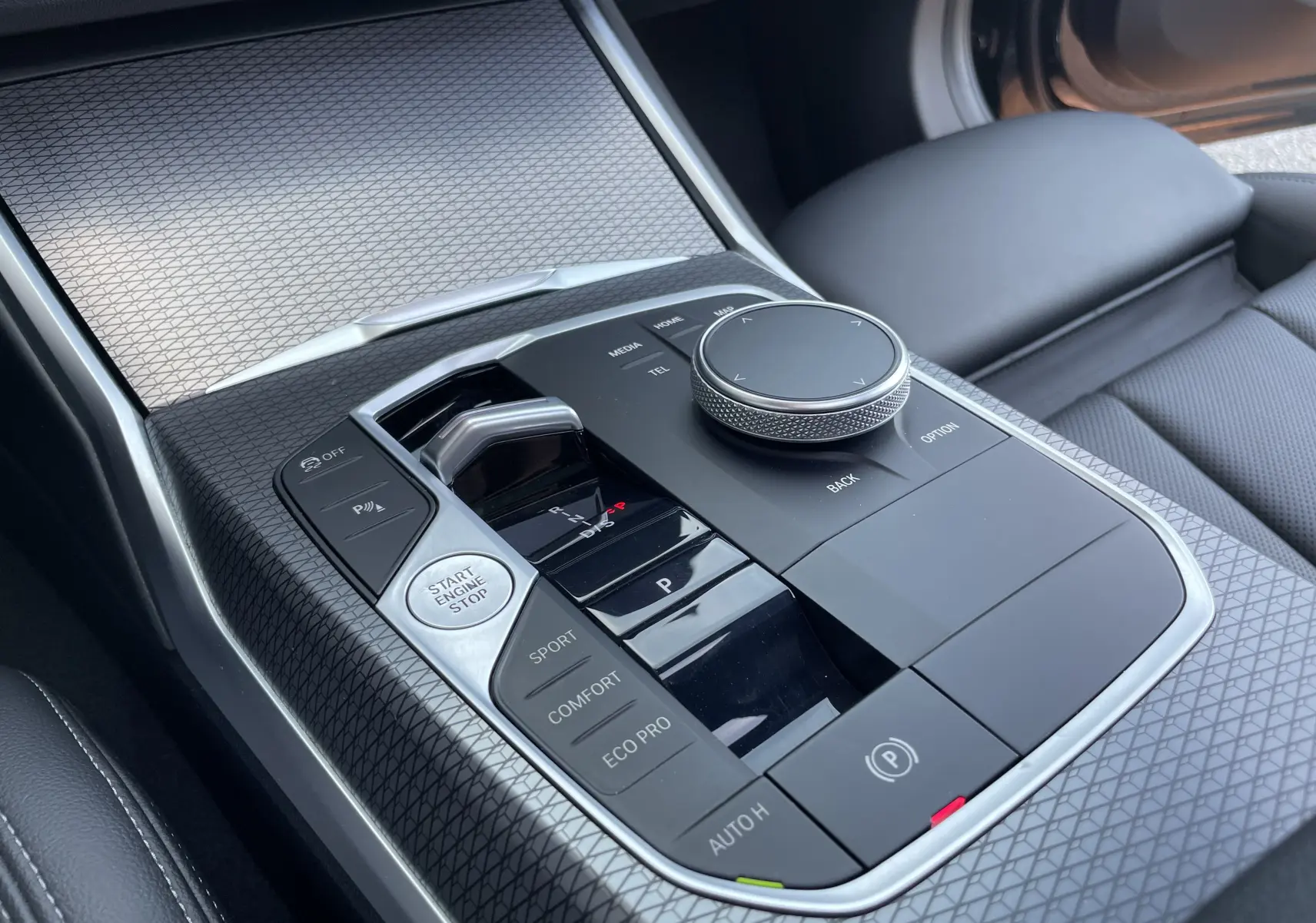 Gros plan sur la console centrale noire avec commandes de boîte auto et molette de contrôle du BMW Série 3 Touring G21.