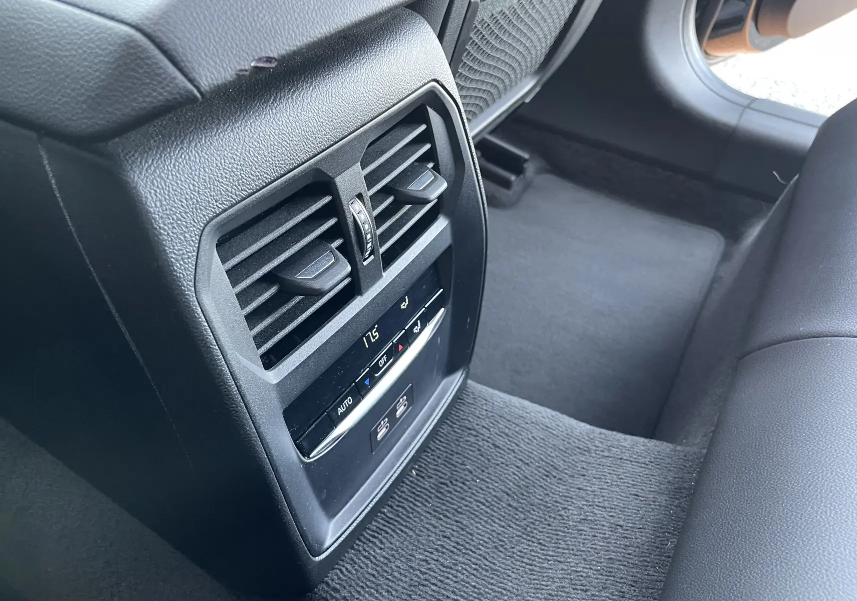 Détail de la console arrière noire avec commandes de climatisation et bouches d'aération dans une BMW Série 3 Touring G21 2022.