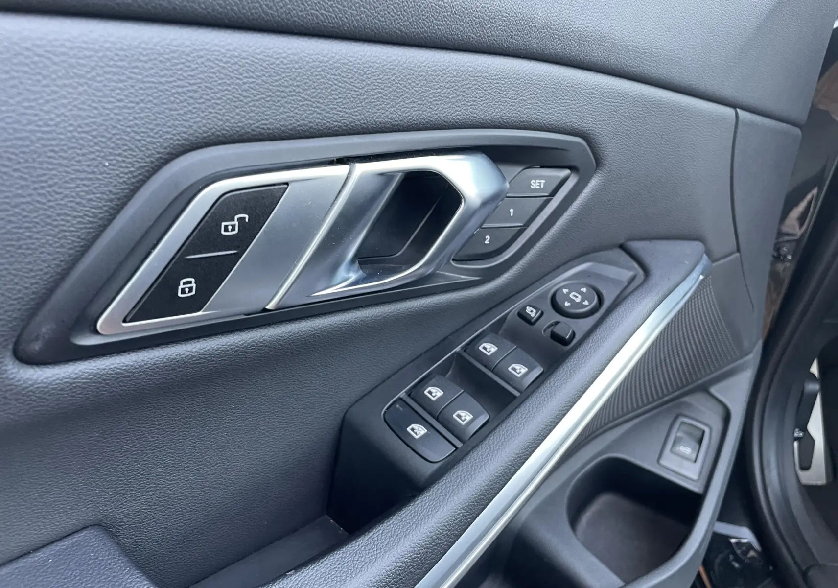 Détail de la porte avant gauche noire métal de la BMW Série 3 Touring G21 avec commandes de vitres et réglages mémoire des sièges.