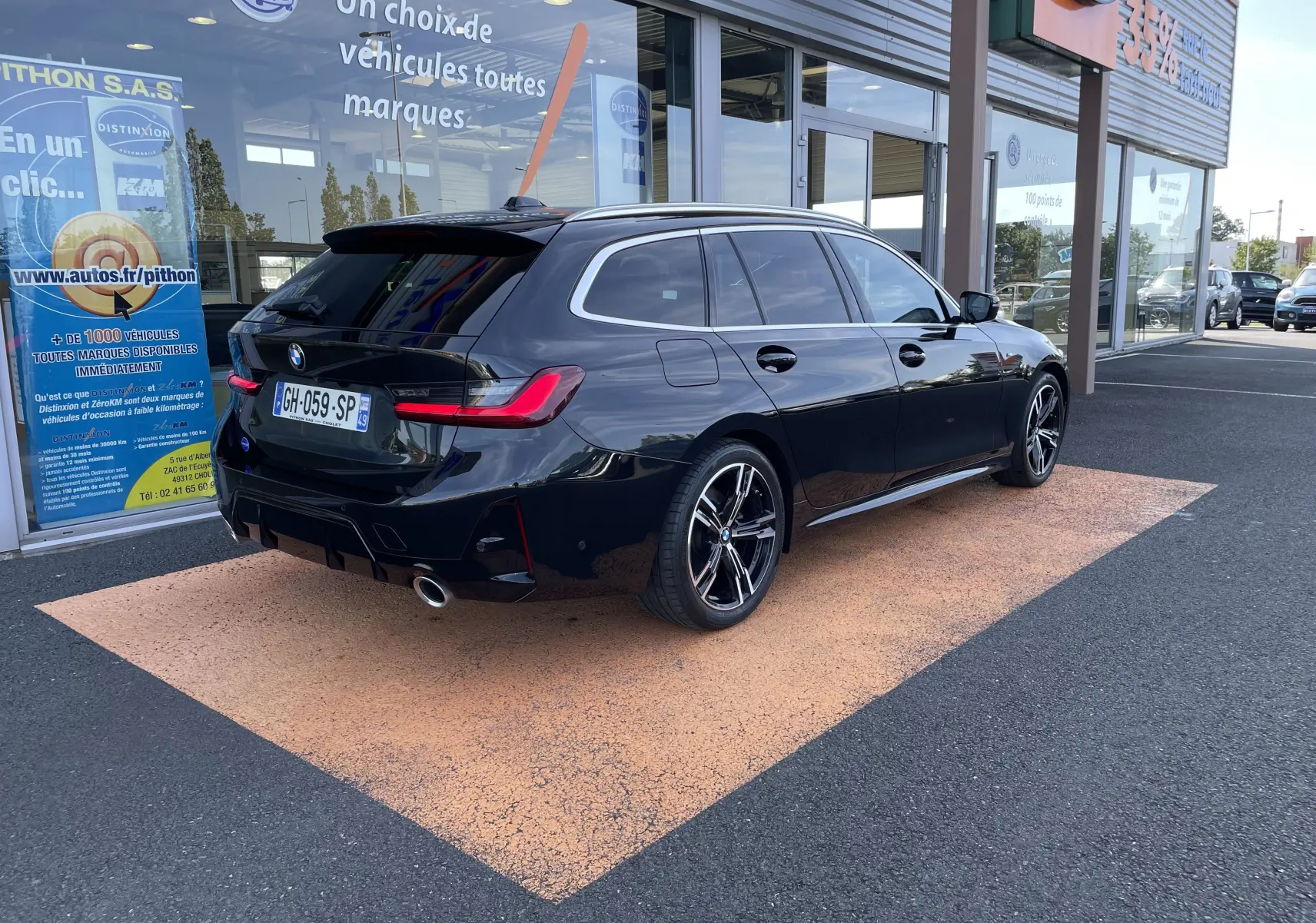 BMW Série 3 Touring G21 noir métal vue 3/4 arrière droit, avec jantes M Sport et feux arrière LED allumés.