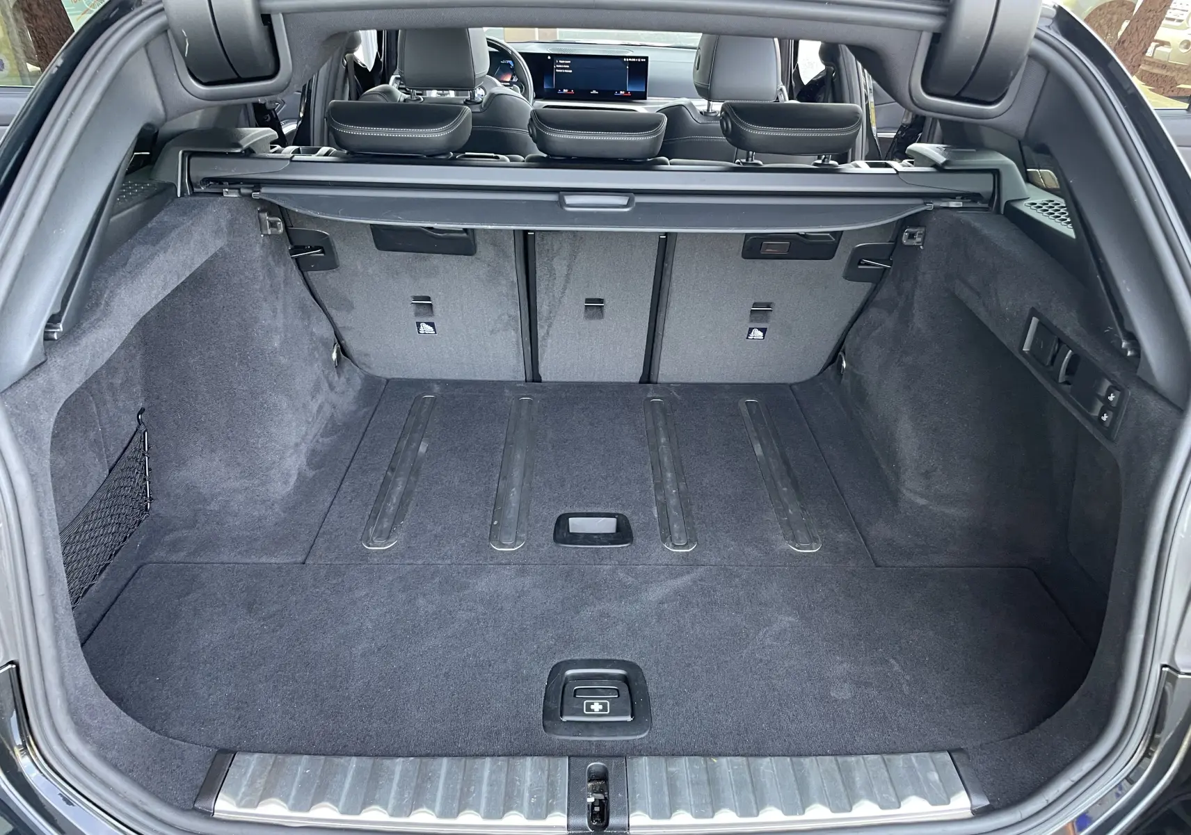 Coffre ouvert d'une BMW Série 3 Touring G21 noire métal, montrant l'espace de chargement et la banquette arrière rabattue partiellement.