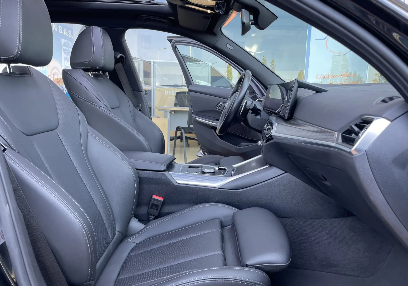 Intérieur noir cuir de la BMW Série 3 Touring G21 XDrive 190 M Sport 2022, vue côté conducteur avec toit ouvrant panoramique.