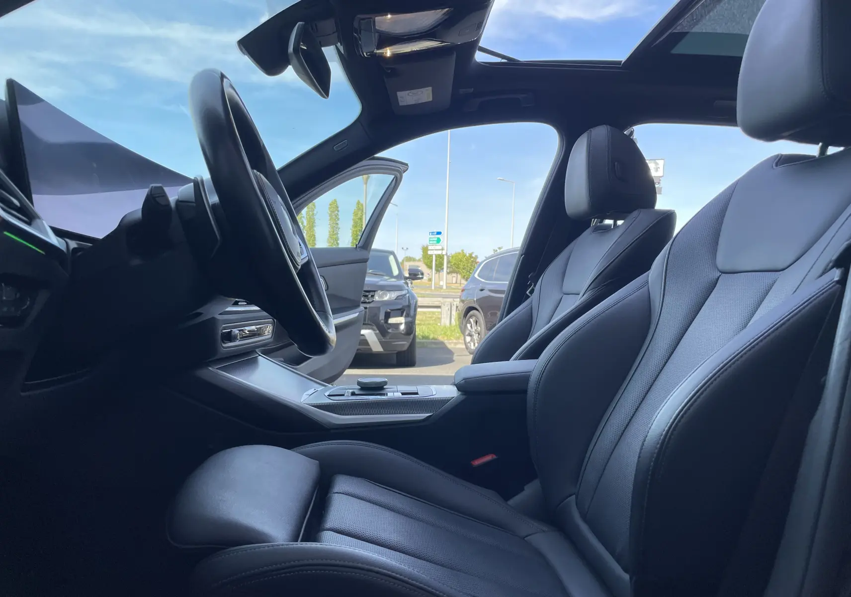 Intérieur noir cuir de la BMW Série 3 Touring G21 XDrive 190 M Sport, vue côté conducteur avec toit ouvrant panoramique.
