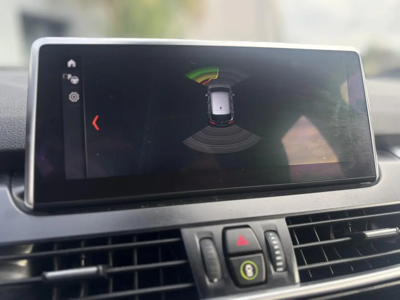 Écran central du tableau de bord montrant l'aide au stationnement avec vue aérienne du véhicule BMW Série 2 Active Tourer.