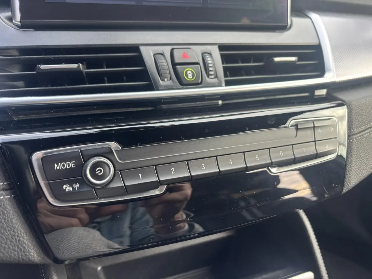 Détail de la console centrale noire brillante de la BMW Série 2 Active Tourer 218dA avec boutons de mode et mémoire radio.