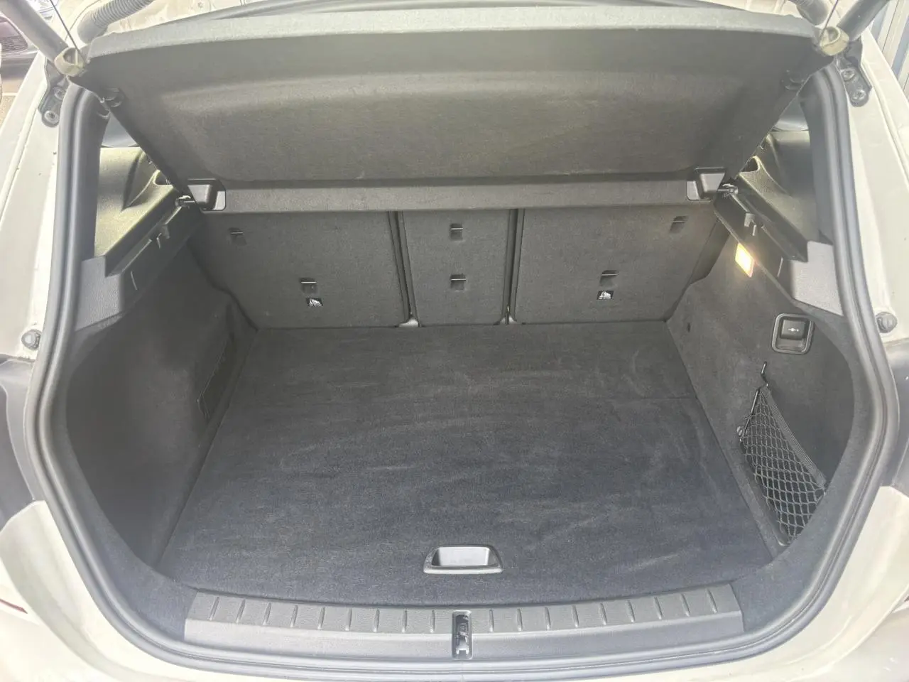 Coffre ouvert d'une BMW Série 2 Active Tourer blanche, montrant un espace de chargement propre et bien éclairé.