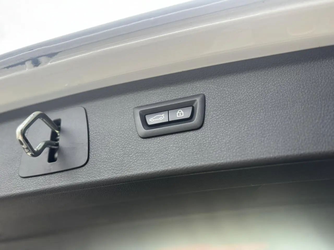 Gros plan sur le hayon blanc de la BMW Série 2 Active Tourer 218dA avec bouton d'ouverture électrique et serrure visible.