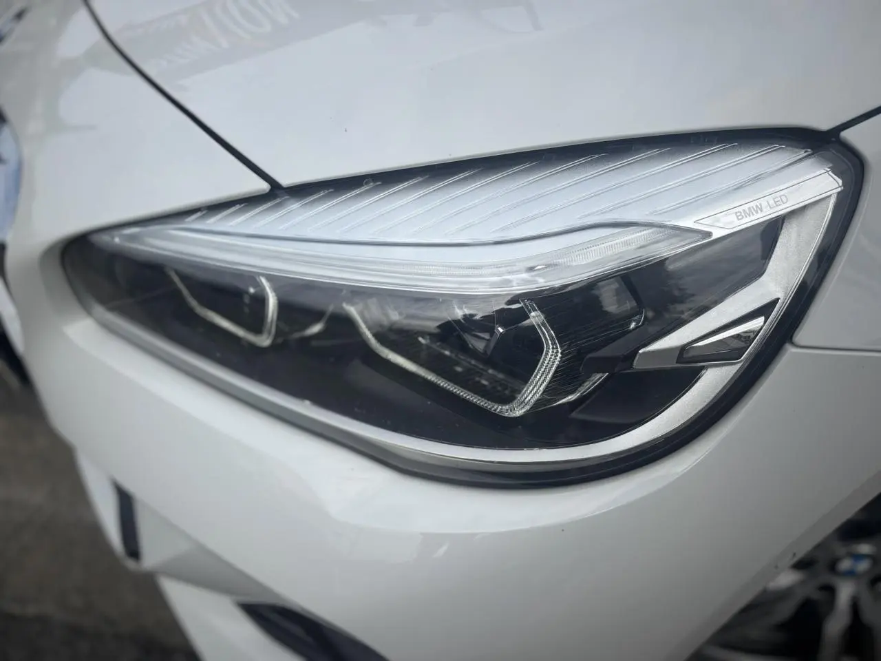 Gros plan sur le phare avant droit blanc d’une BMW Série 2 Active Tourer 218dA M Sport avec éclairage LED distinctif.