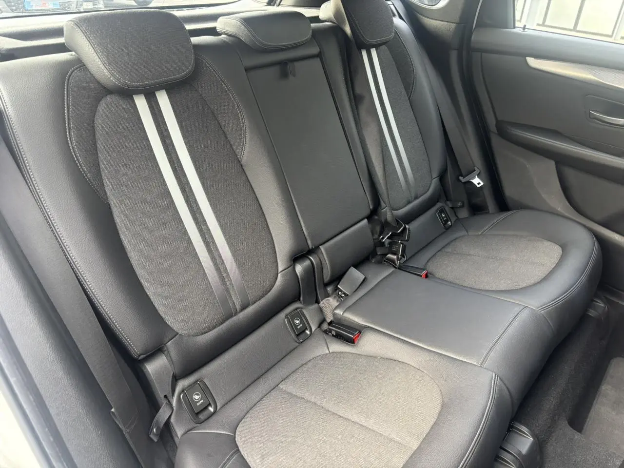 Vue intérieure côté droit des sièges arrière gris foncé avec bandes claires au centre dans une BMW Série 2 Active Tourer blanche.