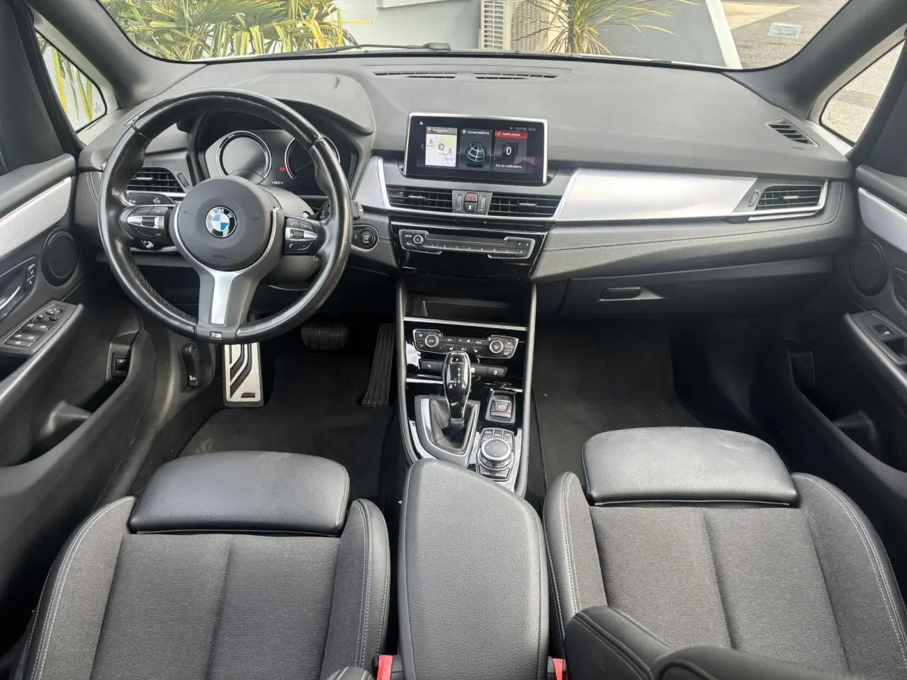 Vue intérieure avant de la BMW Série 2 Active Tourer 218dA 2020, tableau de bord noir avec écran GPS central et volant cuir M.