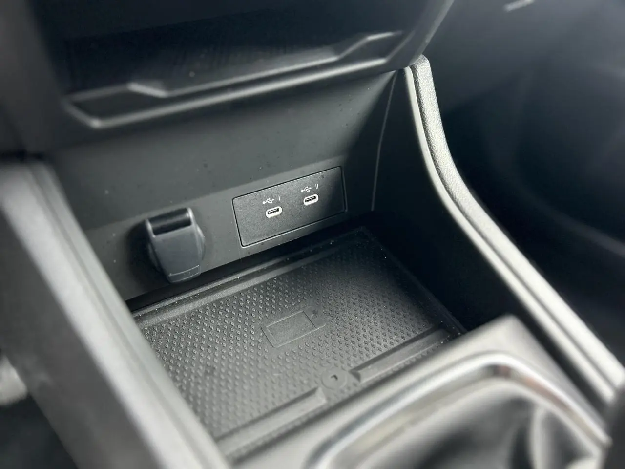 Gros plan sur la console centrale noire du Renault Captur 2025, montrant les ports USB-C et la zone de charge sans fil.