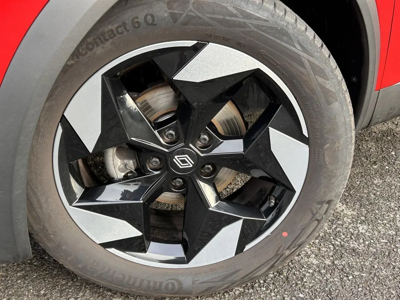 Gros plan sur la jante alu 18 pouces diamantée noire du Renault Captur Rouge Flamme avec partie de la carrosserie visible.