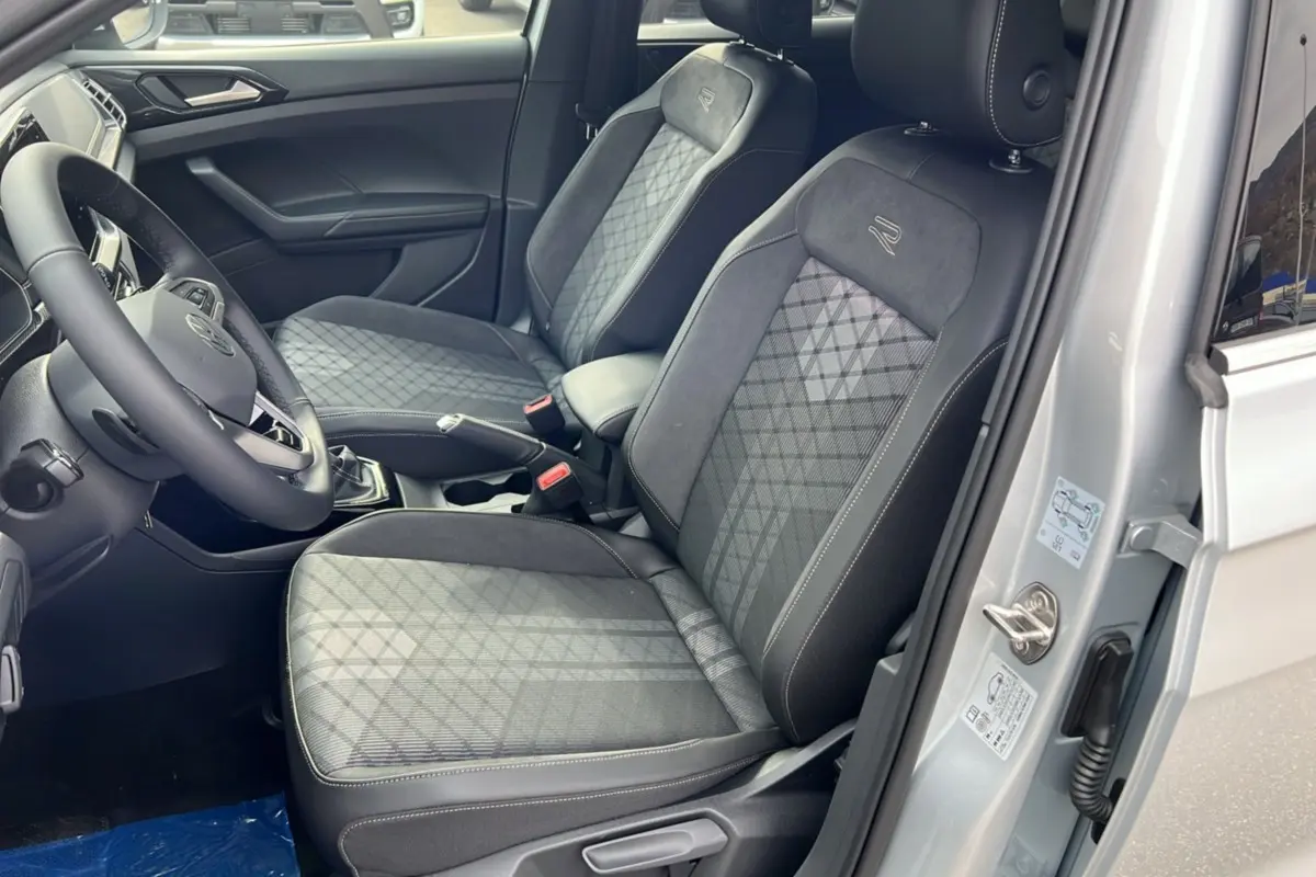 Vue intérieure côté conducteur du Volkswagen T-cross gris argent 2025 avec sièges tissu R-Line et volant cuir multifonctions.