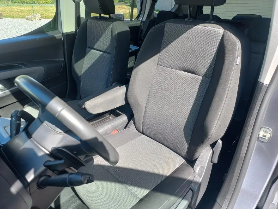 Vue intérieure côté conducteur du Toyota Proace City Verso gris 2023, mettant en valeur le siège tissu et l'accoudoir.