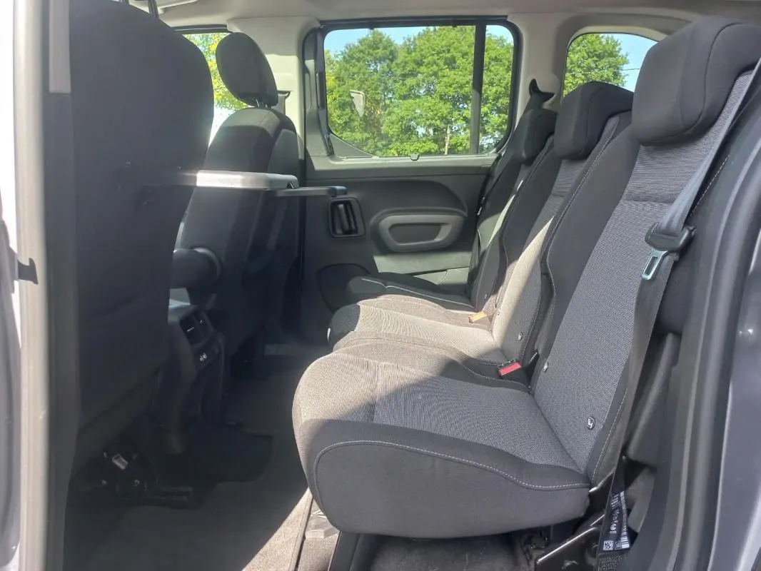 Vue latérale intérieure côté droit du Toyota Proace City Verso gris 2023, montrant la banquette arrière et une tablette rabattable.