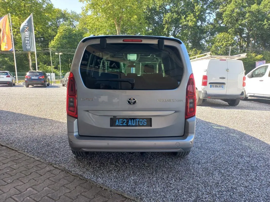 Vue arrière d'un Toyota Proace City Verso gris 2023, avec vitres teintées et plaque AE2 AUTOS visible.