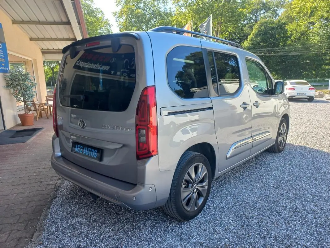 Vue 3/4 arrière droite d'un Toyota Proace City Verso gris 2023, finition Medium Executive avec vitres teintées et jantes alliage.