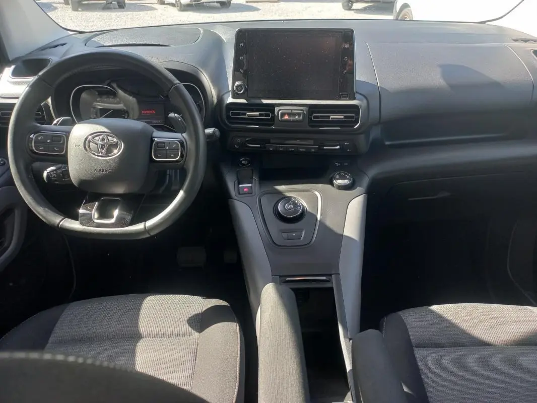 Vue intérieure avant du Toyota Proace City Verso gris 2023, mettant en valeur le tableau de bord et le volant multifonction.