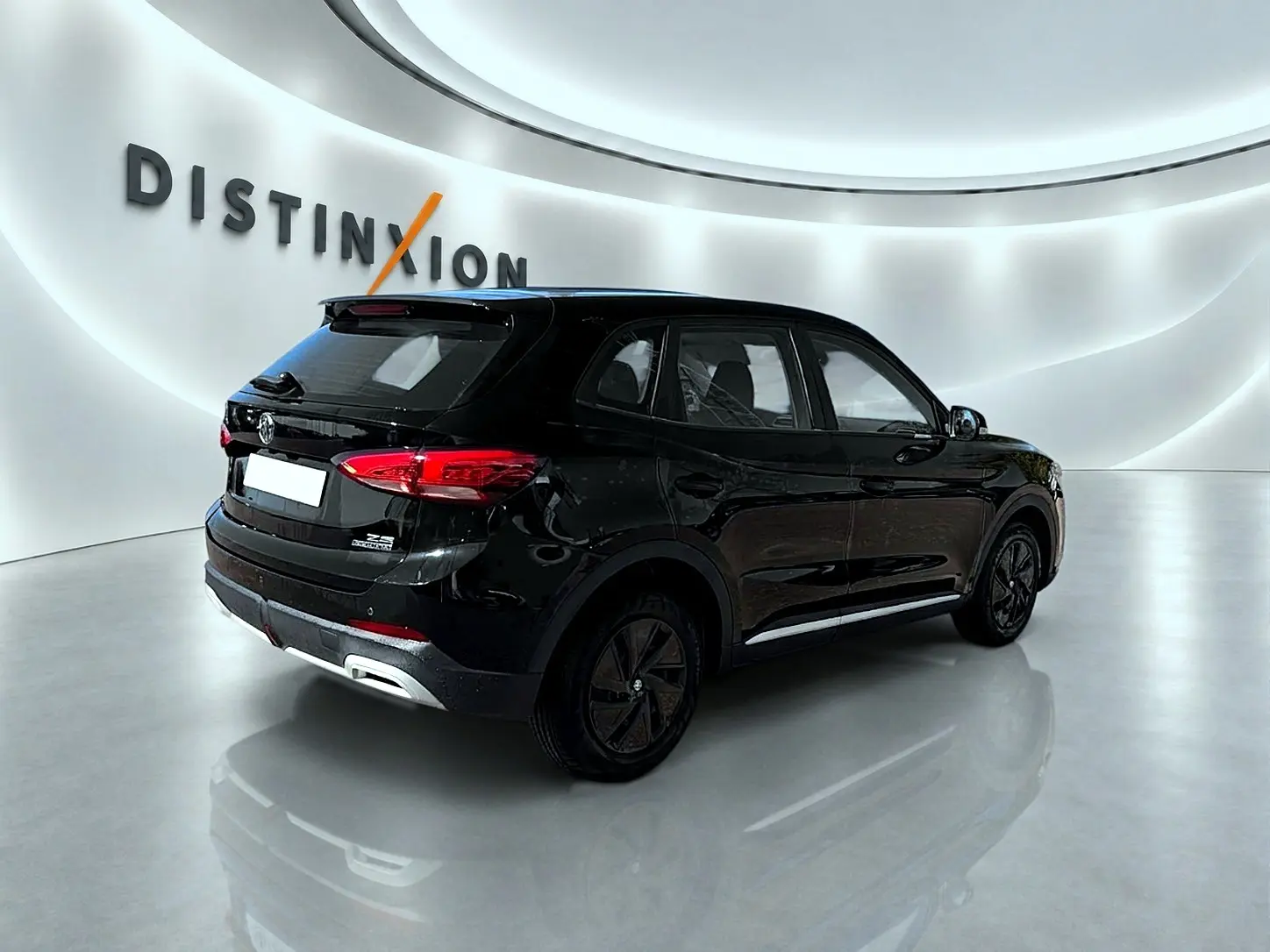 Vue 3/4 arrière droite du SUV MG ZS hybride noir, avec feux arrière LED et becquet arrière visible dans un showroom lumineux.