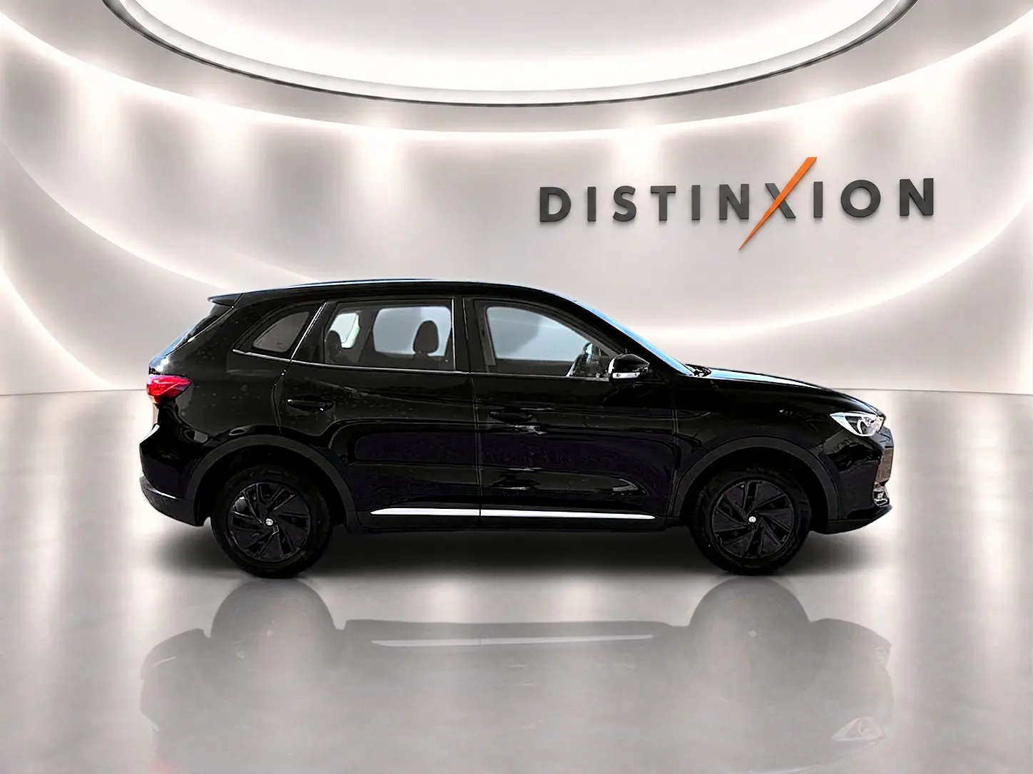 Vue de profil côté gauche du MG ZS 1.5 hybrid noir, avec jantes noires et becquet arrière dans un showroom lumineux.