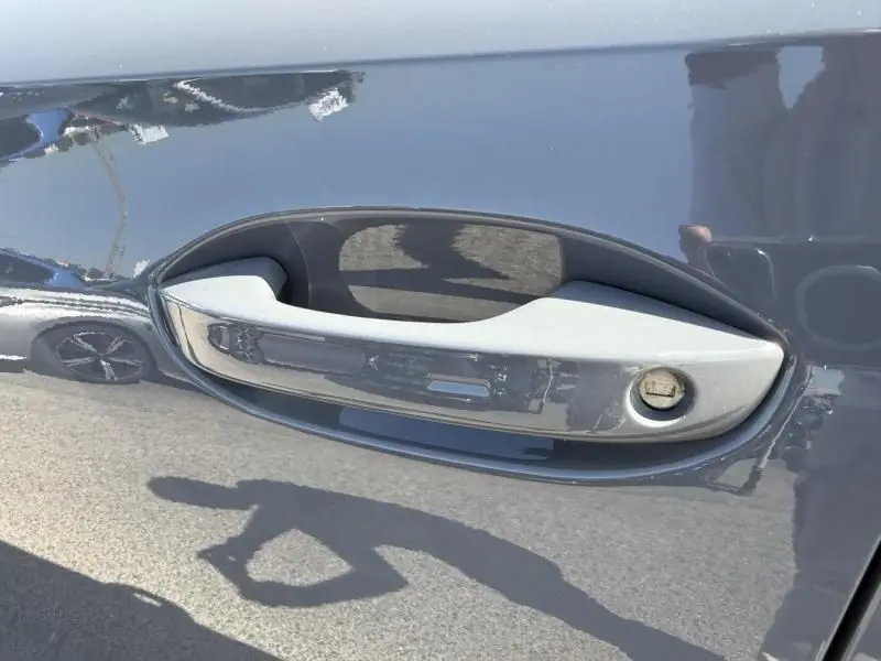 Poignée de porte grise en gros plan sur une CUPRA Formentor 1.4 e Hybrid 2023, reflet du véhicule sur la carrosserie gris foncé.